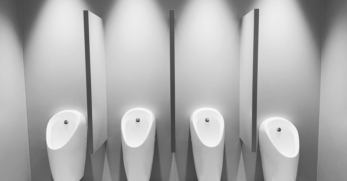A clean and modern restroom featuring four white urinals and partitions.