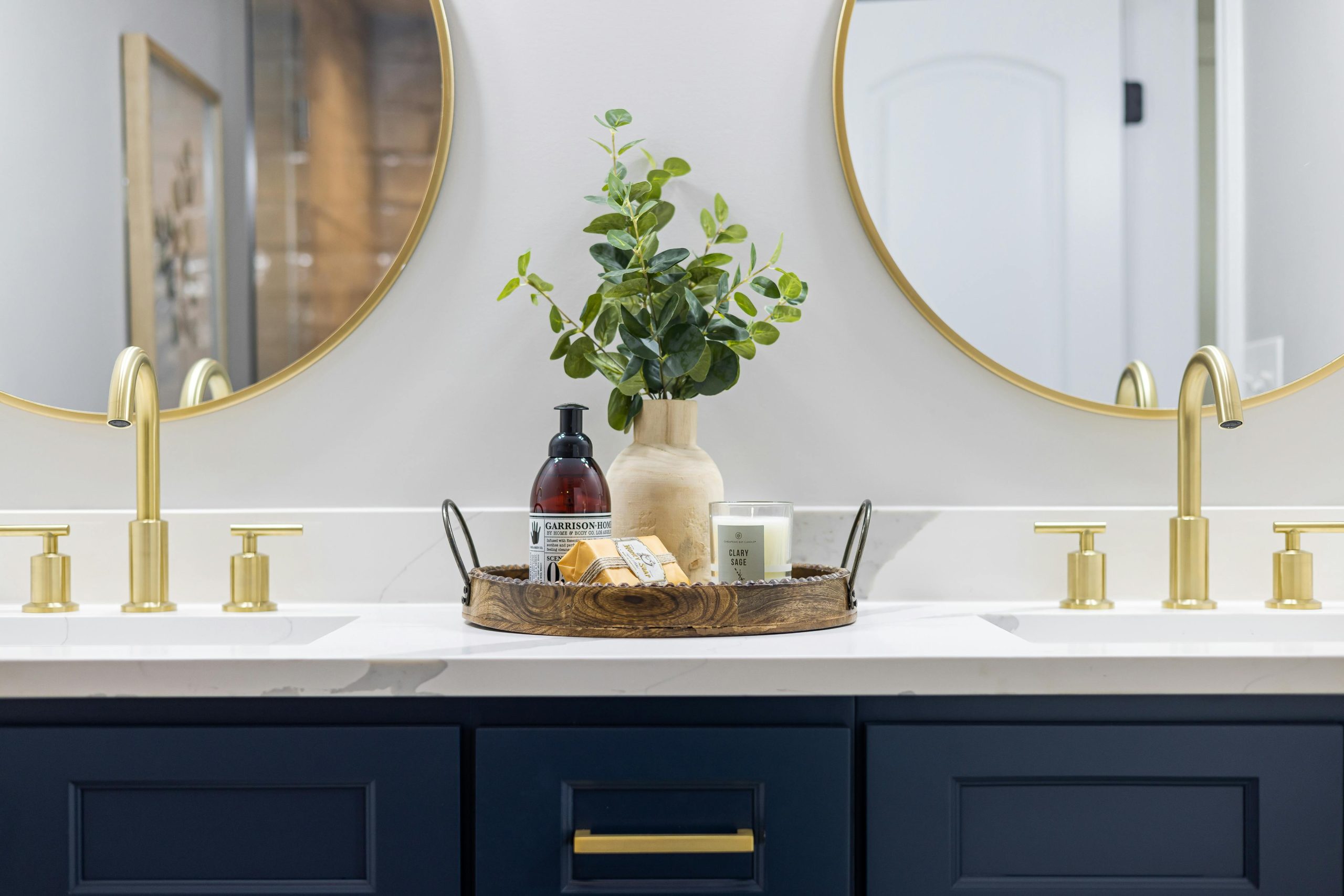 Luxurious bathroom vanity featuring gold faucets, round mirrors, and chic decor.