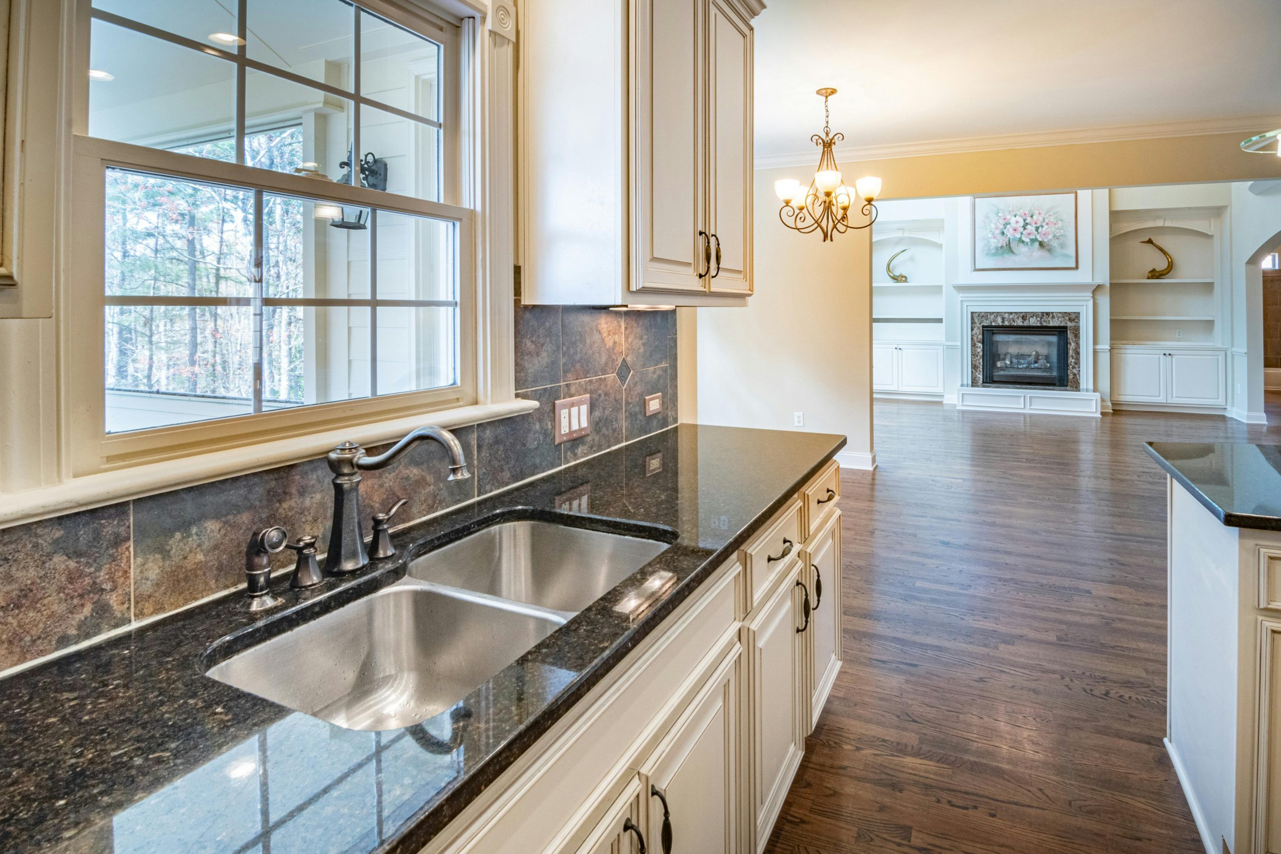 Spacious kitchen with granite countertops, stainless steel sink, and elegant chandelier lighting.