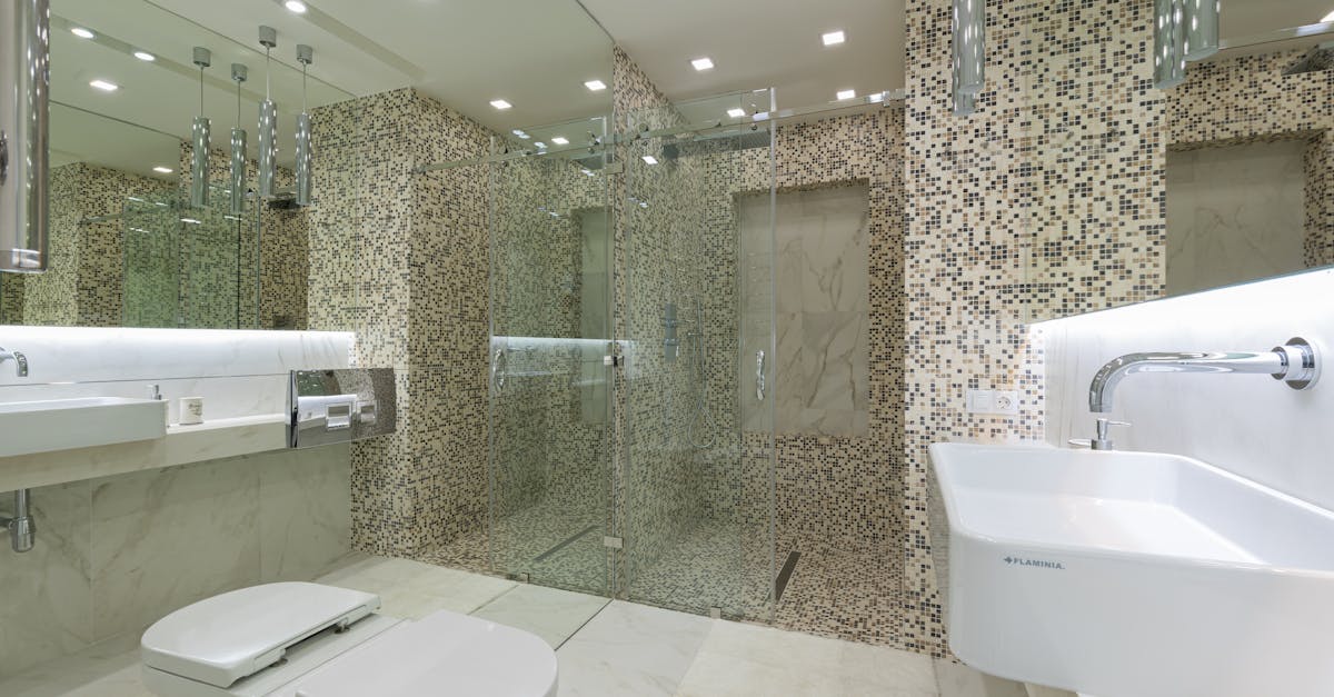 A sleek and spacious modern bathroom featuring elegant mosaic tiles and a glass shower.