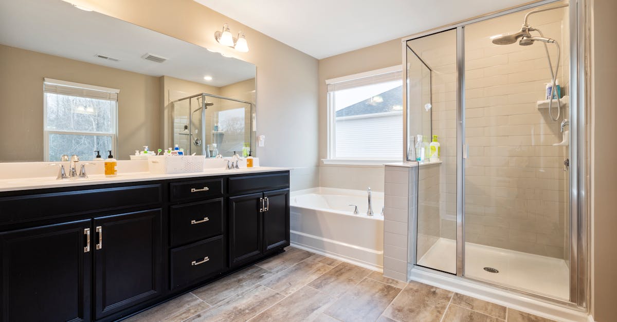 Spacious bathroom featuring a double vanity, bathtub, and glass-enclosed shower with natural light.