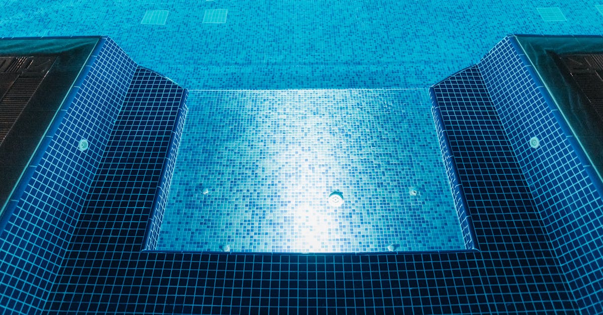 A clear view of an illuminated swimming pool with blue mosaic tiles, perfect for summer relaxation.